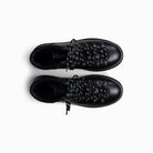 Pair of black leather boots with decorative lacing on a white background