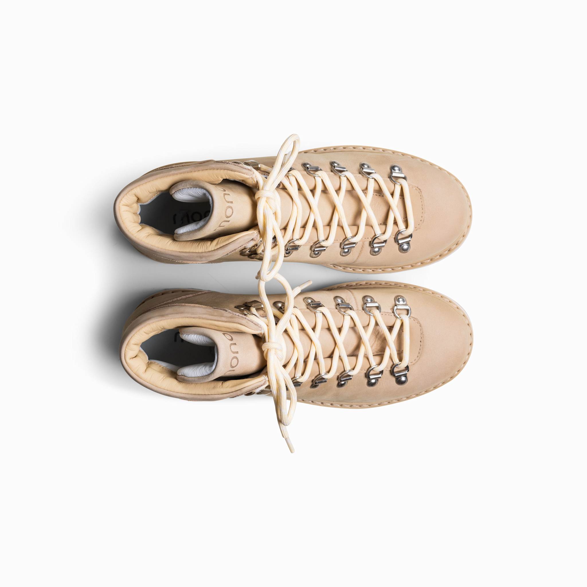 Pair of beige boots with white laces on a white background