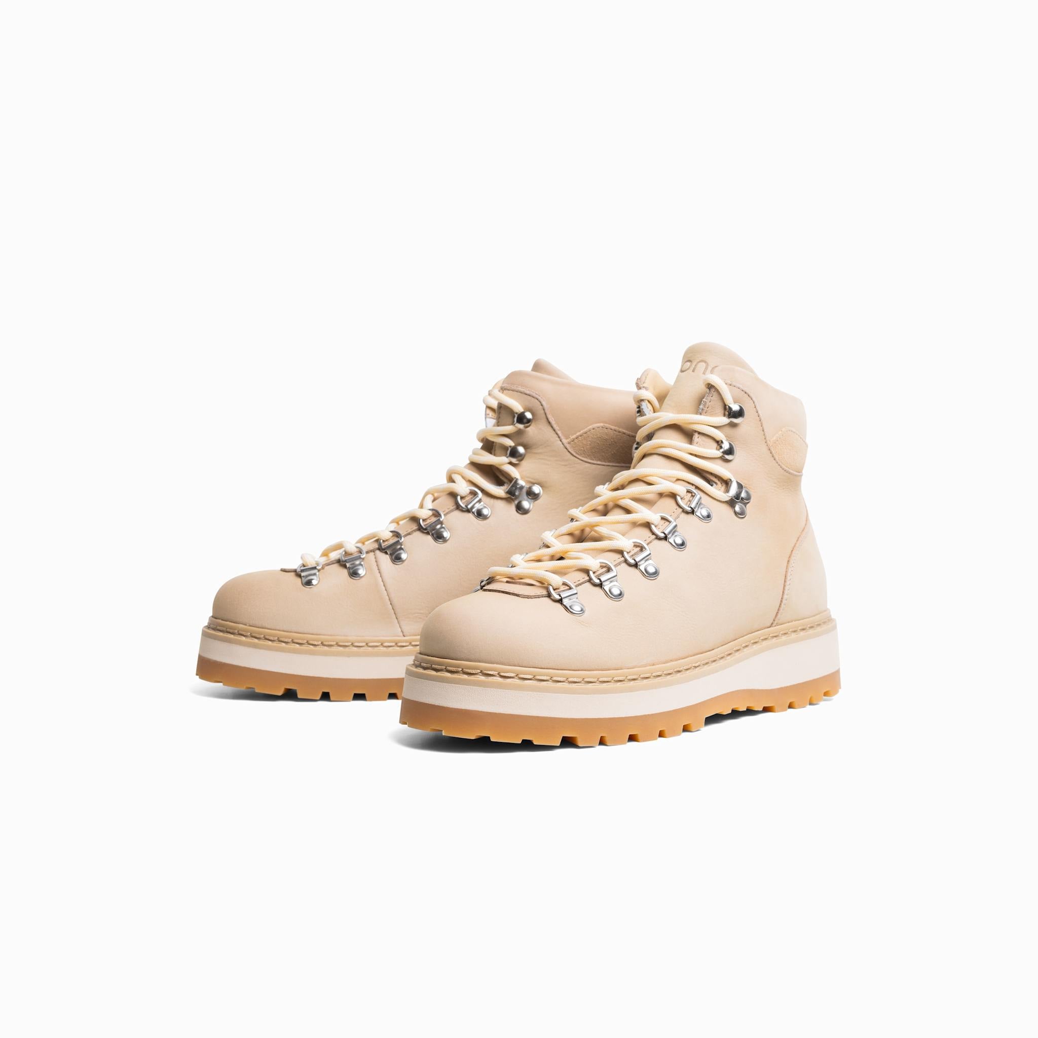 Pair of beige hiking boots with white soles on a light gray background