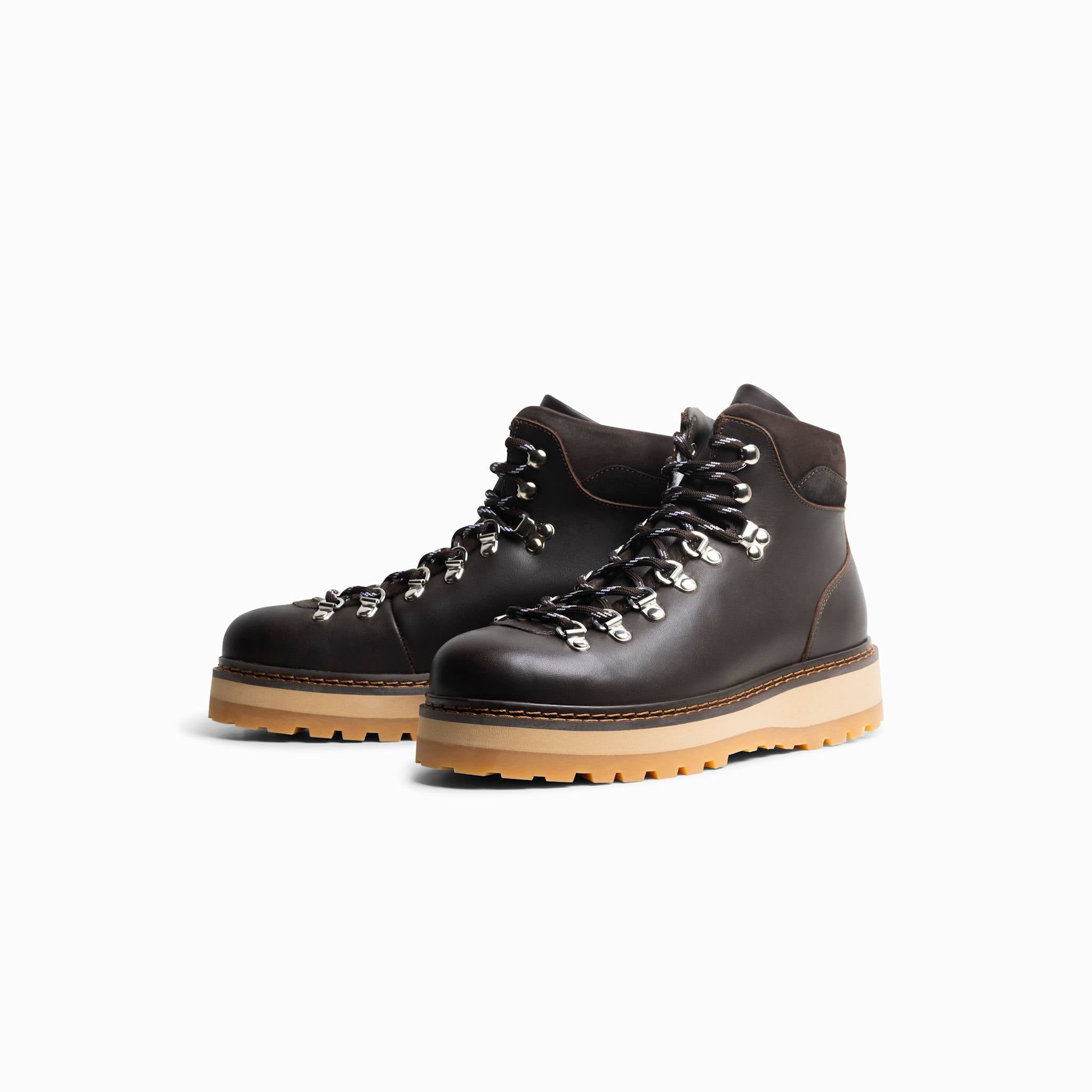 Pair of dark brown hiking boots with tan soles on a white background
