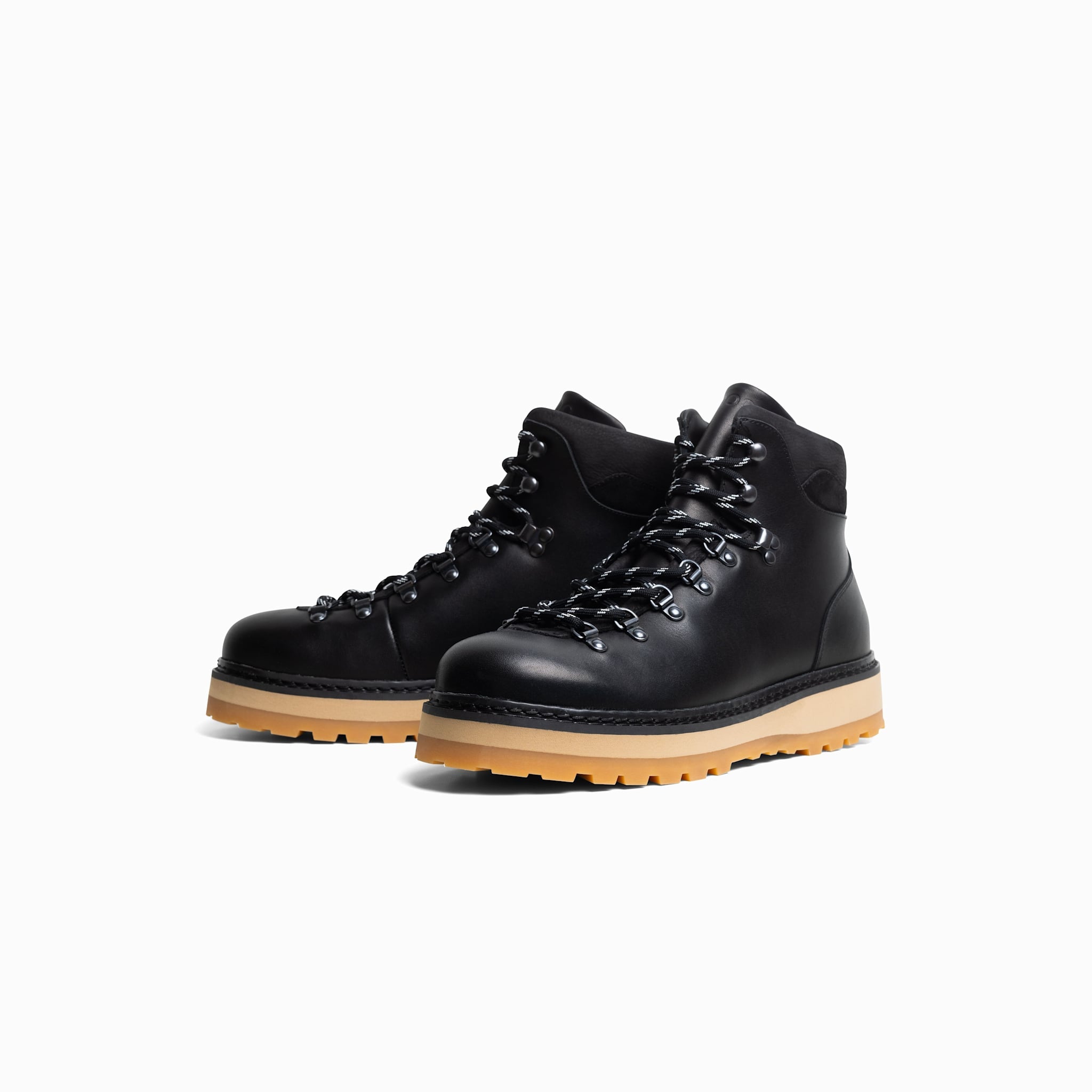 Pair of black leather boots with tan soles on a white background